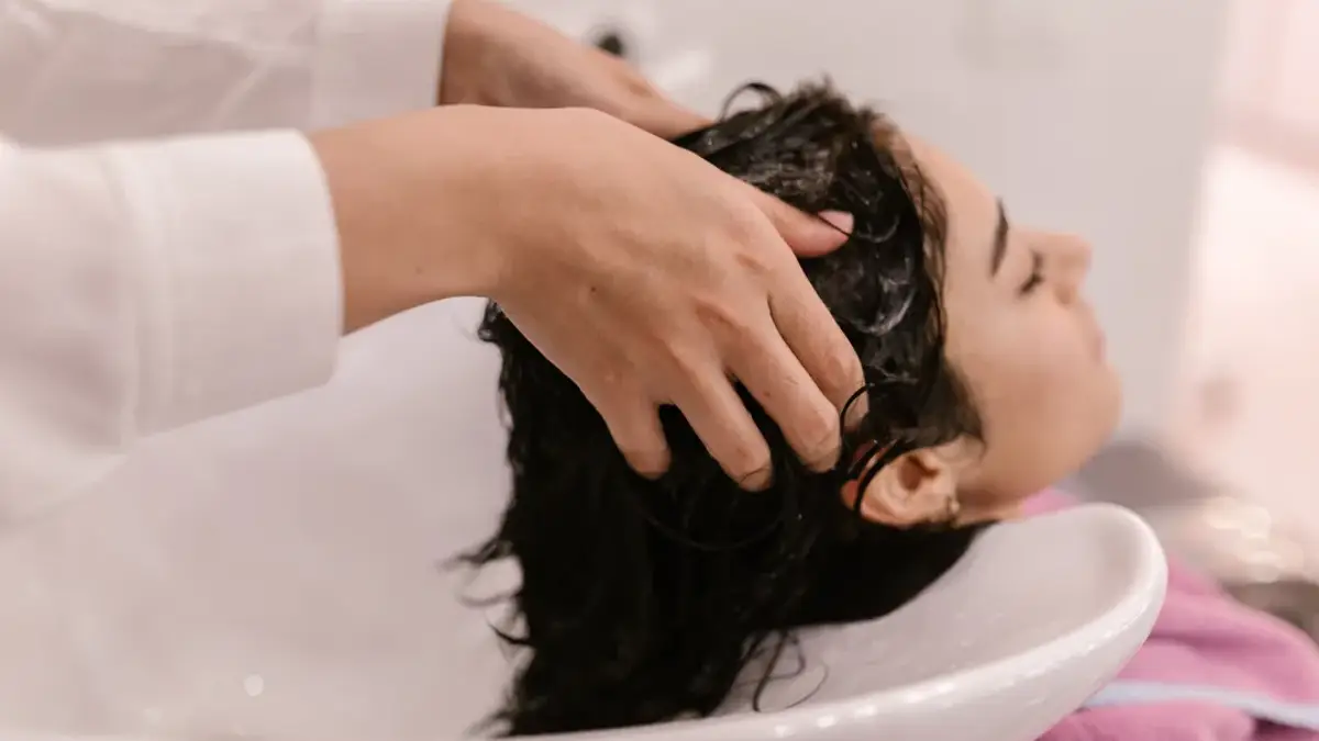 Woman washing hair with shampoo foam