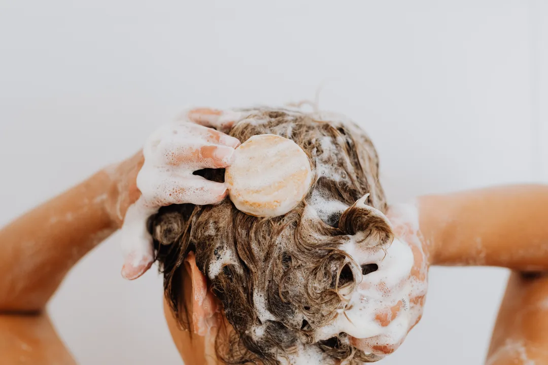 Fingers massaging shampoo lather into the scalp