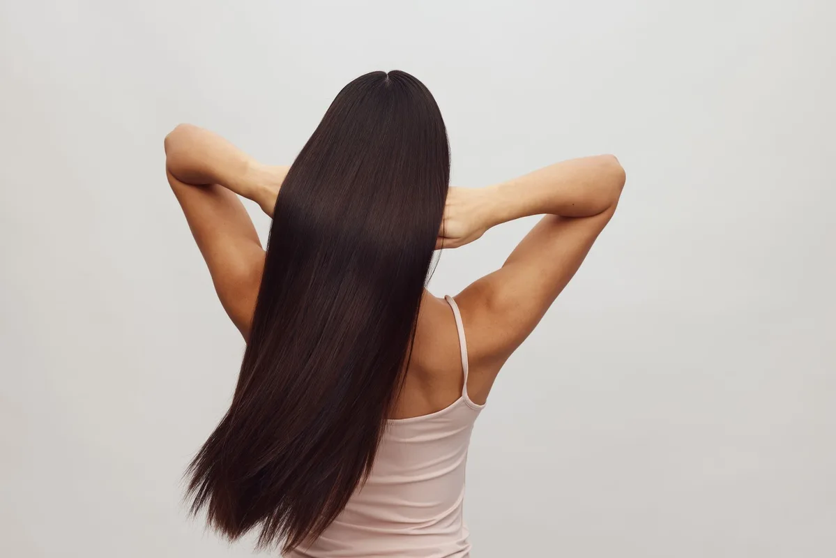 Woman with long sleek glossy dark hair seen from behind