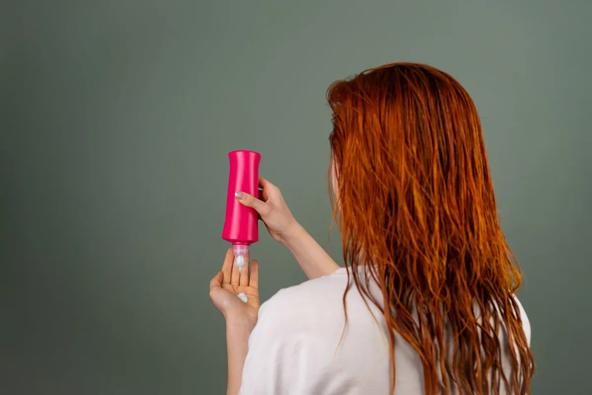 Woman with wet hair applying a conditioning product after washing